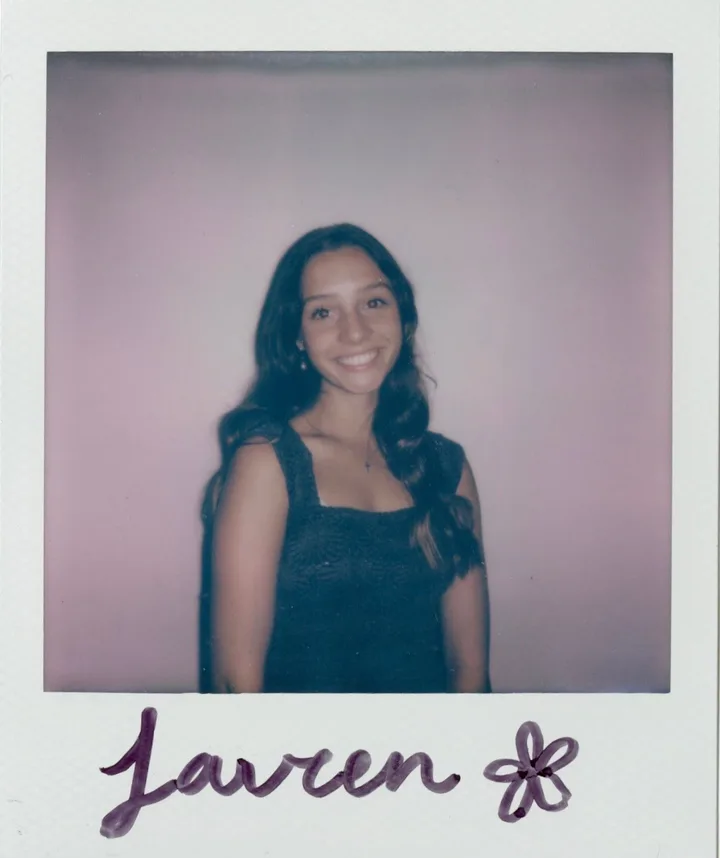 Polaroid photo of Lauren smiling, signed “Lauren” with a little flower